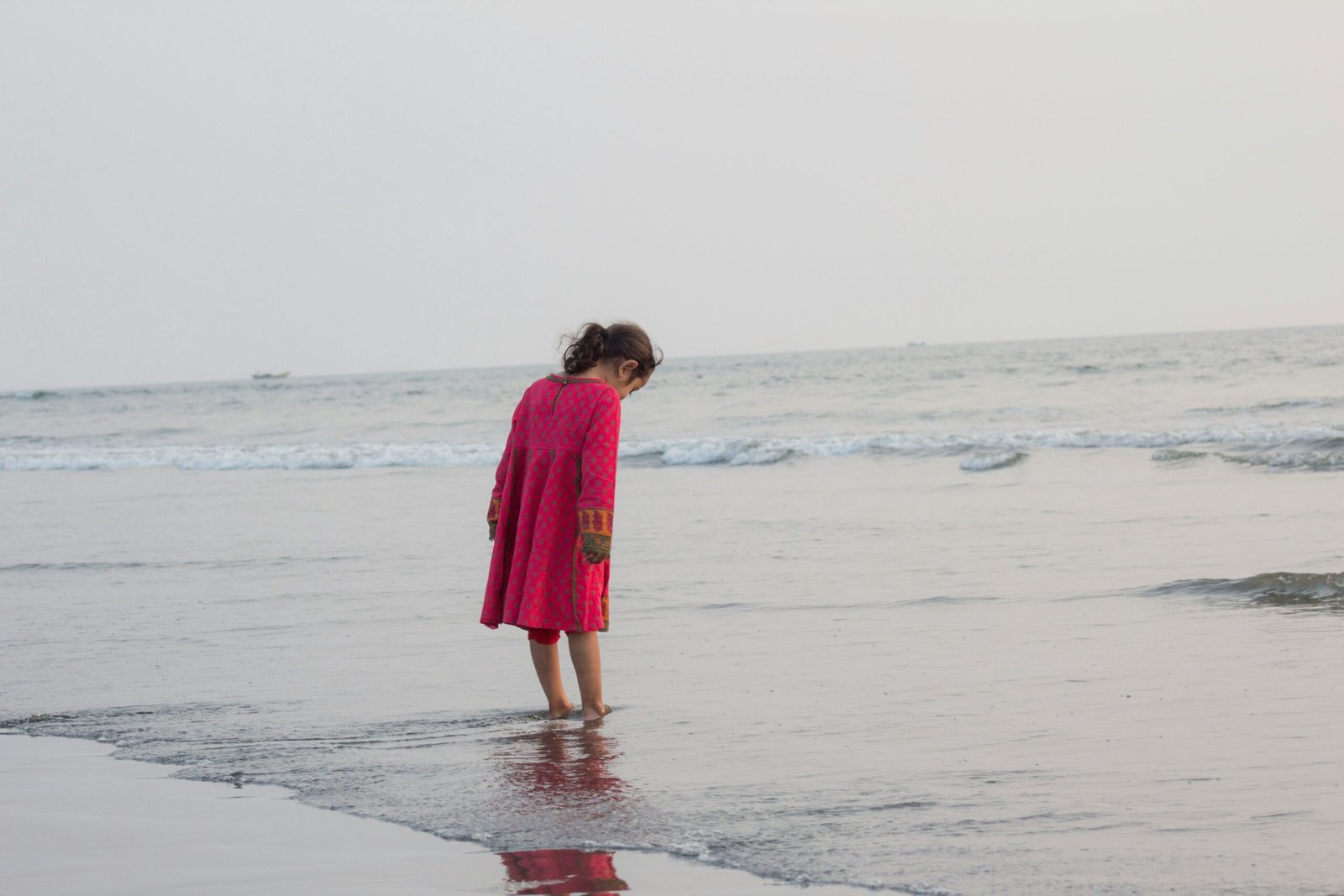 a little girl standing in the water at the beach